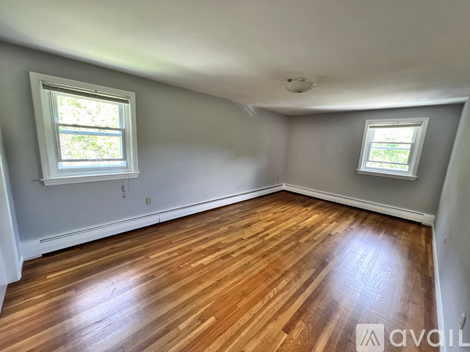 A room with wooden floors and two windows.