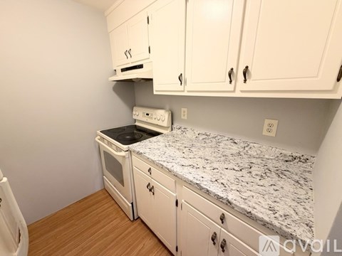 A kitchen with white cabinets and a granite countertop.