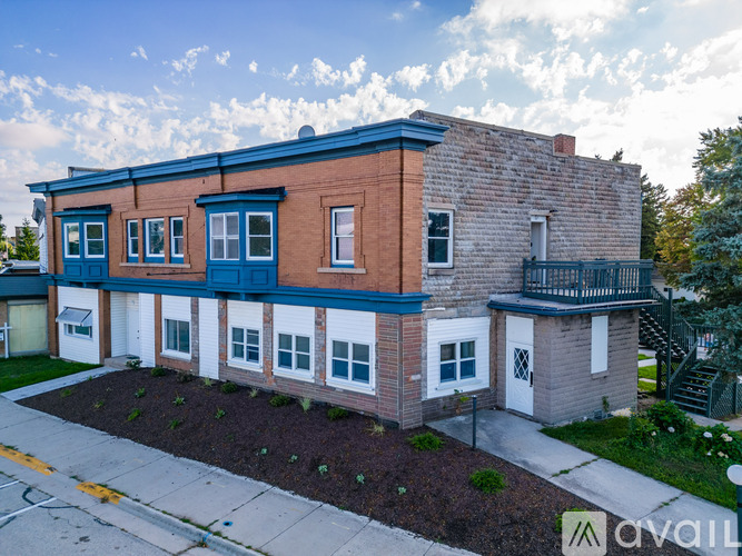 A two-story brick building with blue trim and a balcony on the second floor.