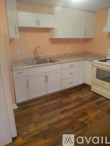 A kitchen with white cabinets and a wooden floor.