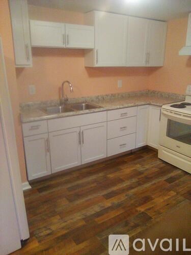A kitchen with white cabinets and a wooden floor.