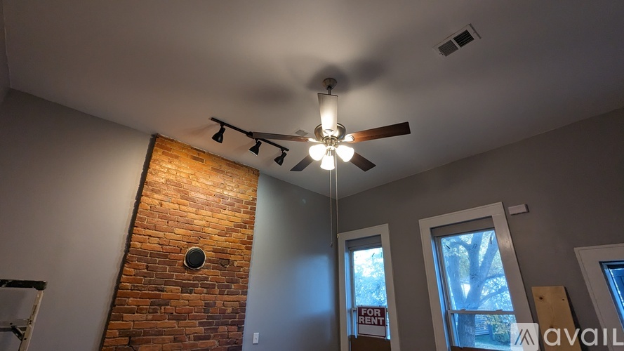 A room with a brick wall and a ceiling fan.