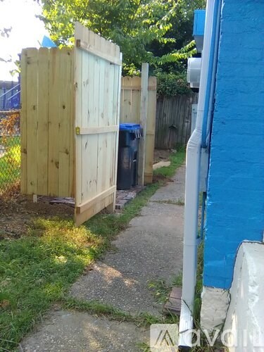 A wooden structure with a door is situated next to a blue wall.
