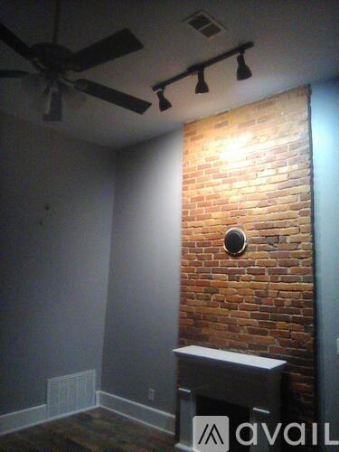 A room with a brick wall and a ceiling fan.