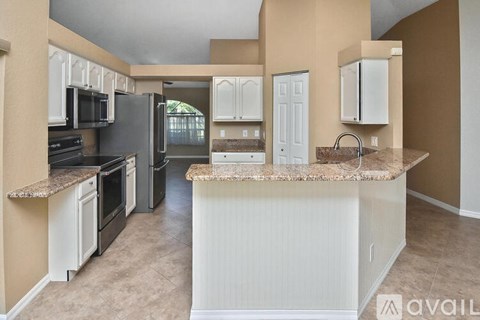 A kitchen with a black refrigerator and white cabinets.