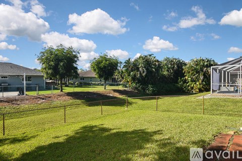 A grassy field with a fence and trees in the background.