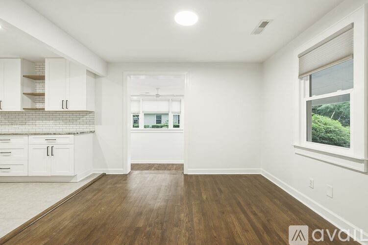 A spacious kitchen with white cabinets and a wooden floor.