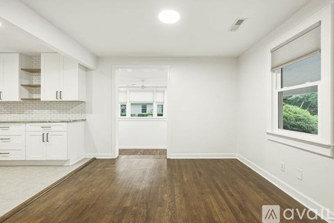 A spacious kitchen with white cabinets and a wooden floor.
