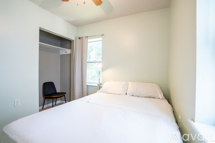 A bedroom with a bed, chair, and window.