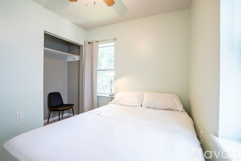 A bedroom with a bed, chair, and window.