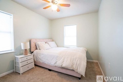 A bedroom with a bed, nightstand, and window.