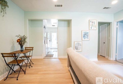 A living room with a couch, a dining table with chairs, and pictures on the wall.