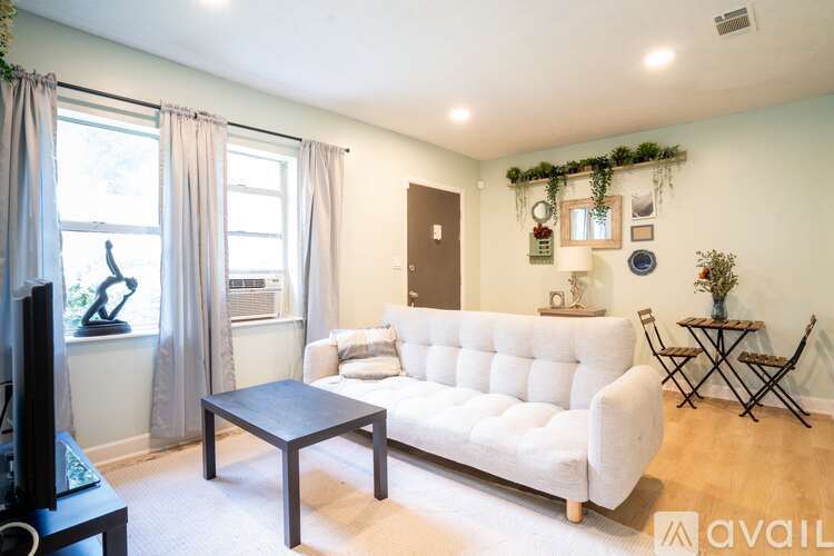 A living room with a white couch, a black coffee table, and a TV.