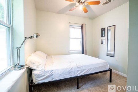 A bedroom with a bed, a window, a lamp and a ceiling fan.