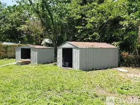 Two grey metal sheds are situated in a grassy area.