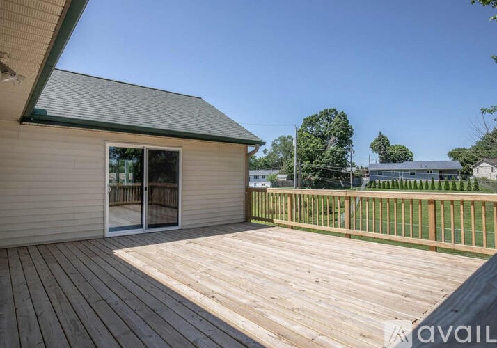 A wooden deck with a house and trees in the background.