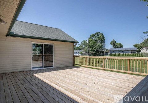 A wooden deck with a house and trees in the background.