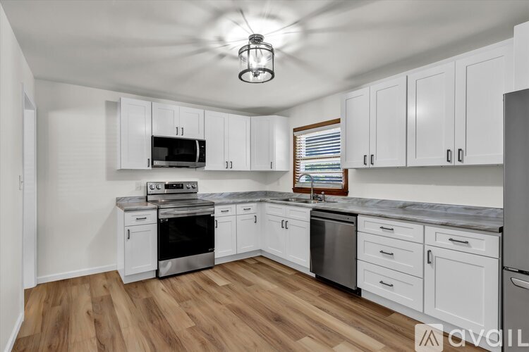 A kitchen with white cabinets and a wooden floor.