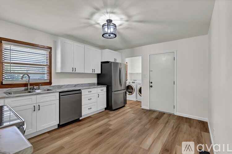 A kitchen with white cabinets and a wooden floor.