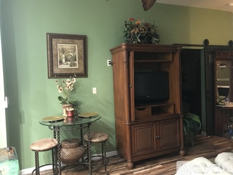 A room with a green wall and a wooden cabinet with a television on top.
