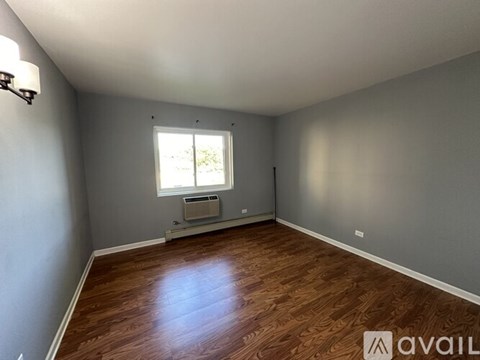 A room with wooden flooring and a window with blinds.
