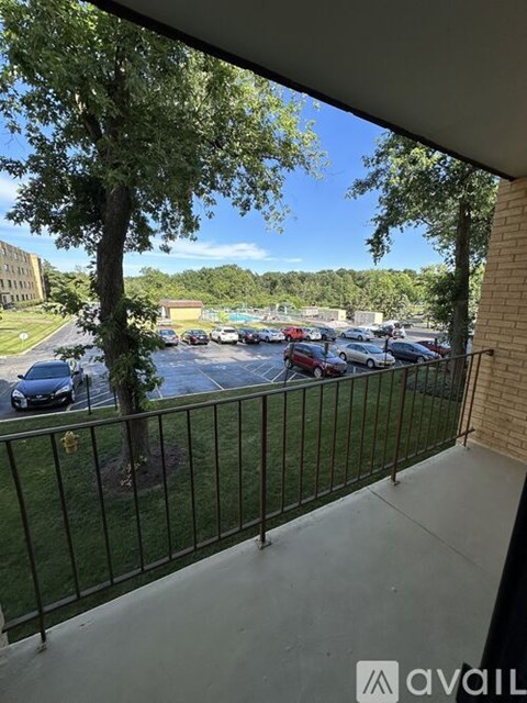 A parking lot with cars and trees is visible from a balcony.
