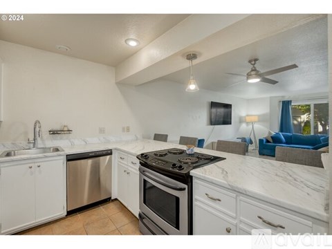 A modern kitchen with white cabinets and a black stove top.