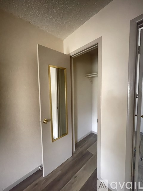 A hallway with a mirror on the wall and a door at the end.