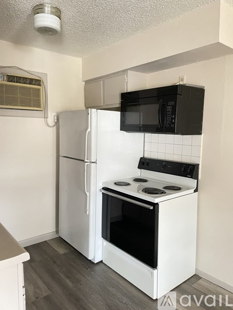 A kitchen with a white refrigerator and black microwave.