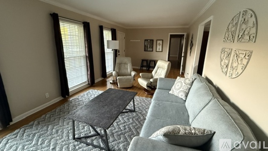 A living room with a grey couch, a black coffee table, and a wall with a circular design.