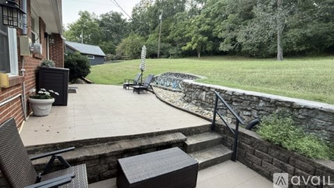 A patio with a table and chairs overlooking a grassy area.