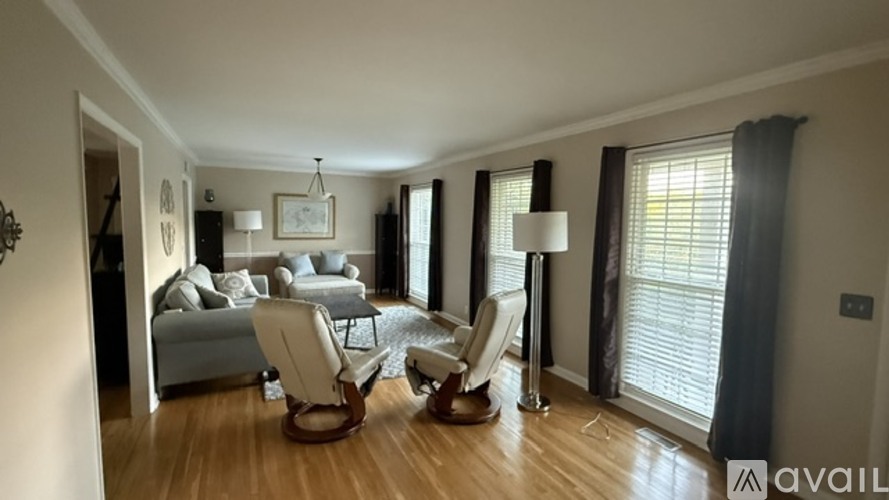 A living room with a grey couch, a brown chair, and a white floor lamp.