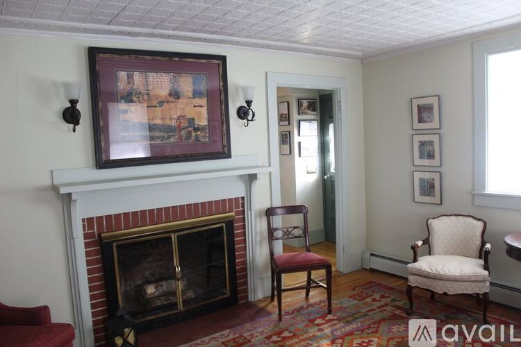 A living room with a fireplace and a painting on the wall.