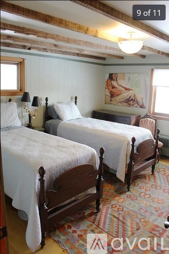 Two twin beds with white bedding in a room with wooden beams on the ceiling.