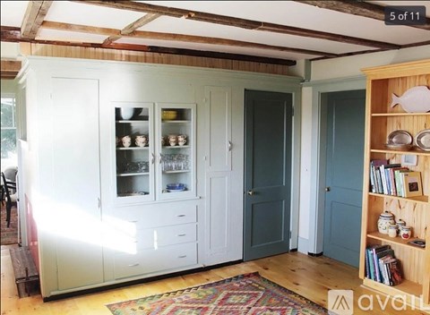 A kitchen with a white cabinet and a wooden shelf.