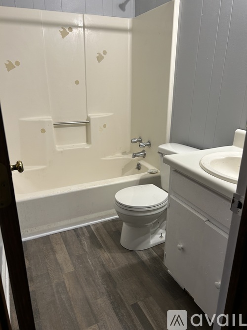 A white toilet sits in a bathroom with a white sink and a white bathtub.