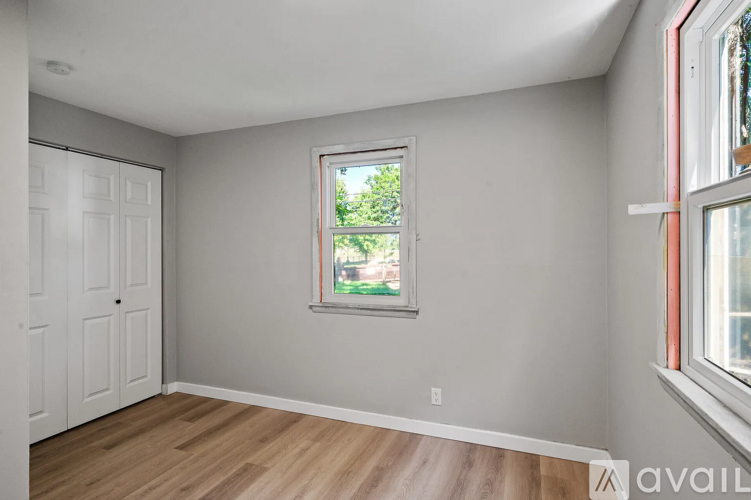 A room with a white door and a window with a view of trees.