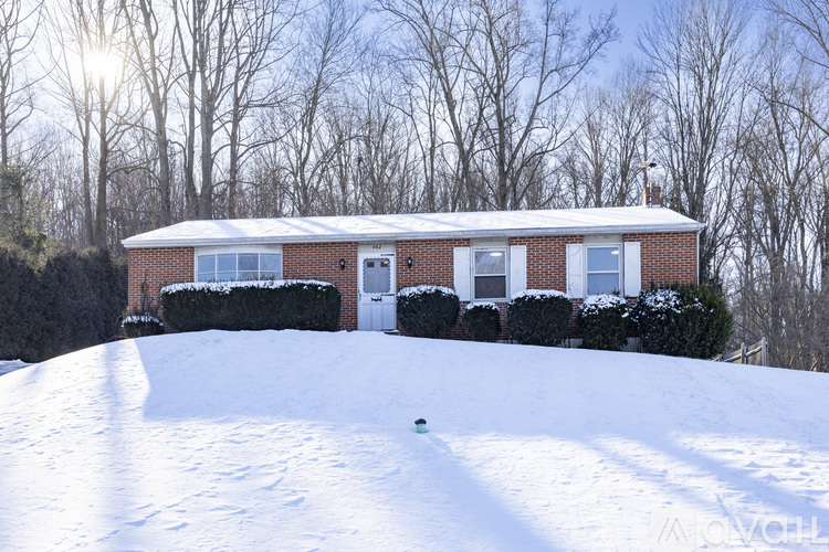 A house with a white door and windows is surrounded by snow.
