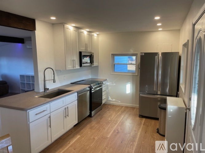 A kitchen with white cabinets and stainless steel appliances is available for rent.