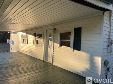 A white house with a wooden deck and a door.