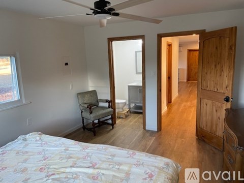 A bedroom with a bed, chair, and a ceiling fan.
