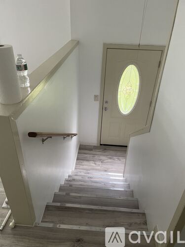 A staircase with a glass balustrade and a round window on the door.