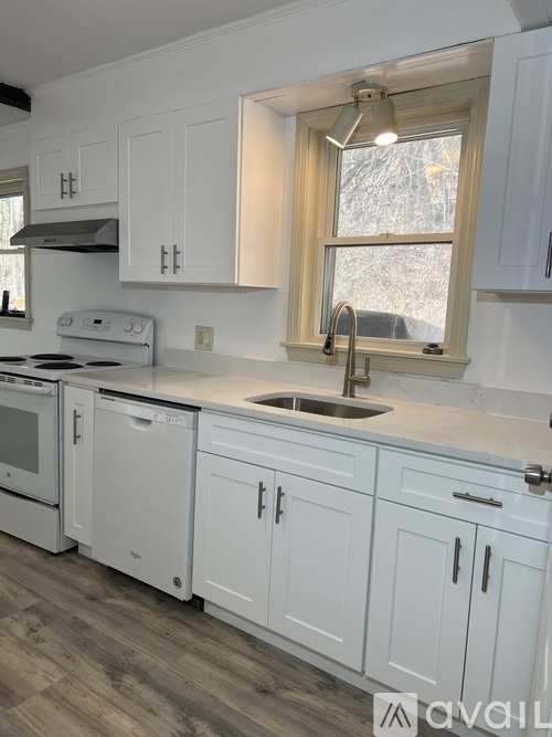 A kitchen with white cabinets and a window.