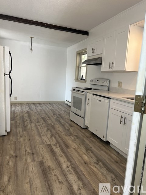 A kitchen with white cabinets and a wooden floor.