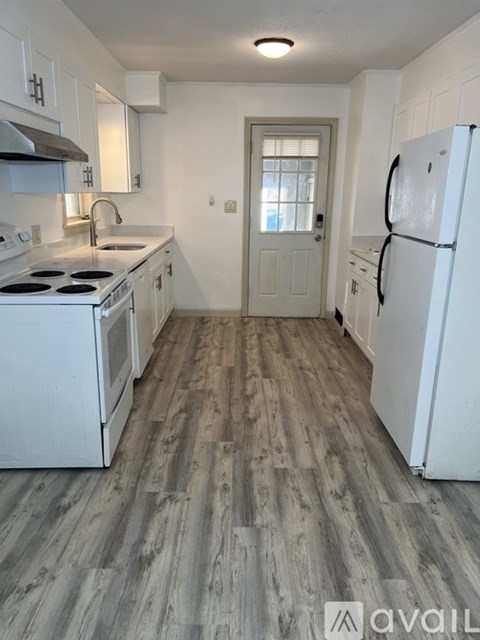 A kitchen with white appliances and wooden floors.