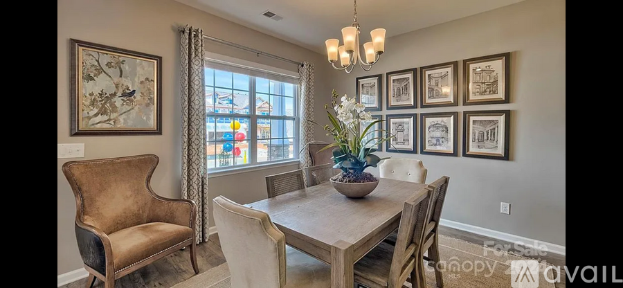 A dining room with a table set for four and a chandelier hanging from the ceiling.