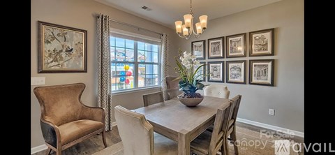 A dining room with a table set for four and a chandelier hanging from the ceiling.