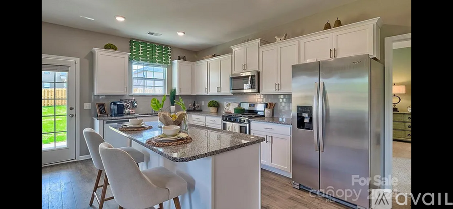 A kitchen with white cabinets and a granite countertop.