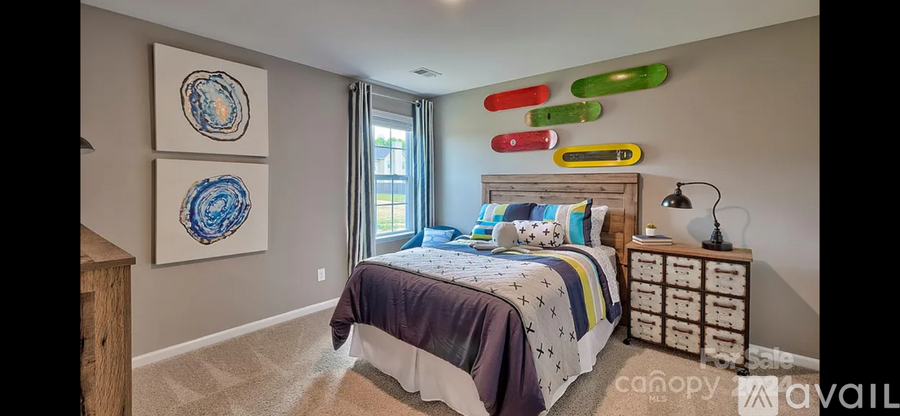 A bedroom with a bed, nightstand, and two paintings on the wall.