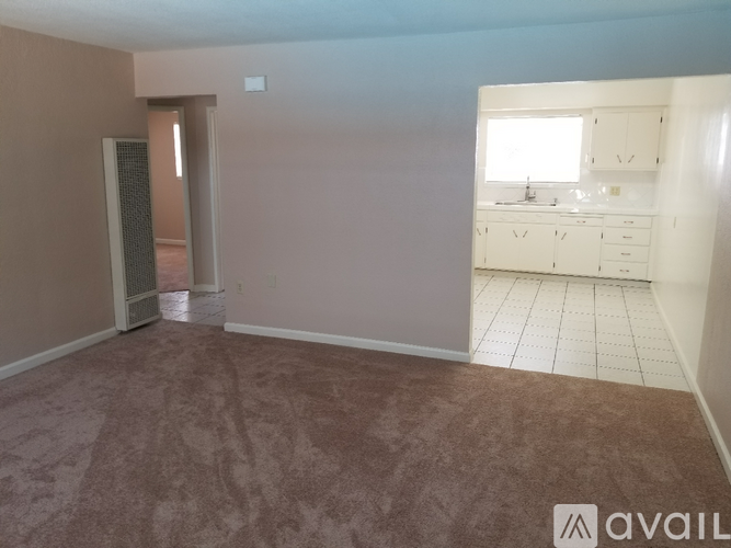 A room with a brown carpet and a white kitchen in the background.